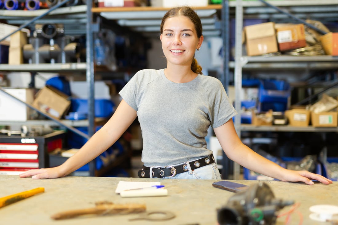 Satisfied female employee of hardware store posing in warehouse